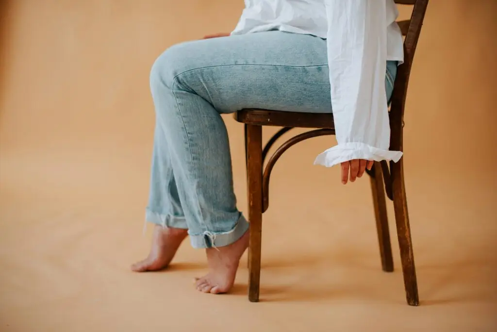 Woman sitting in chair, visible from feet to top of waist.