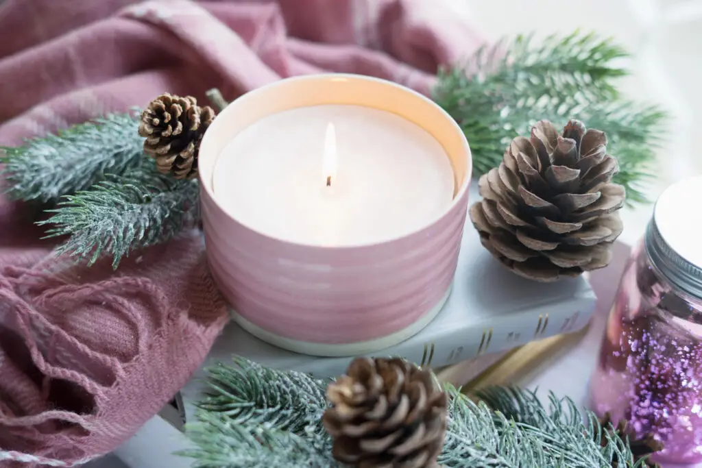 A lit candle with pine cones and pine tree branches