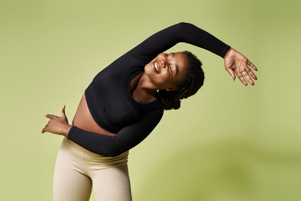 Young woman doing side bend, wearing leggings and fitted top