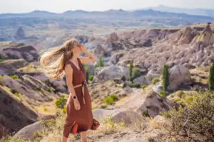 Woman standing in a rocky valley, looking out across an expansive landscape.