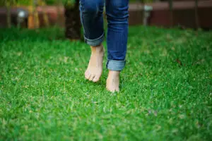 Person walking barefoot on grass to illustrate gentle movement and metabolic health.