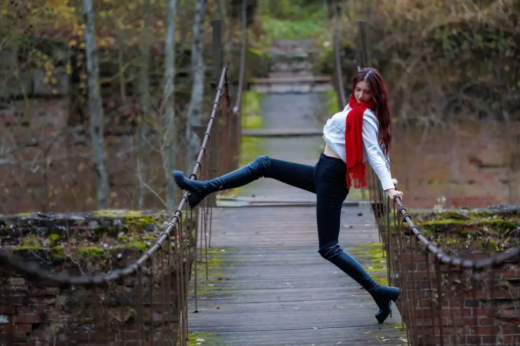 Woman playfully balancing on a suspension bridge in autumn, expressing confidence and authenticity.
