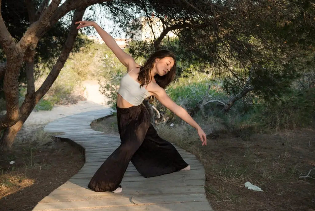 Woman practicing embodied movement and somatic yoga in a natural setting.