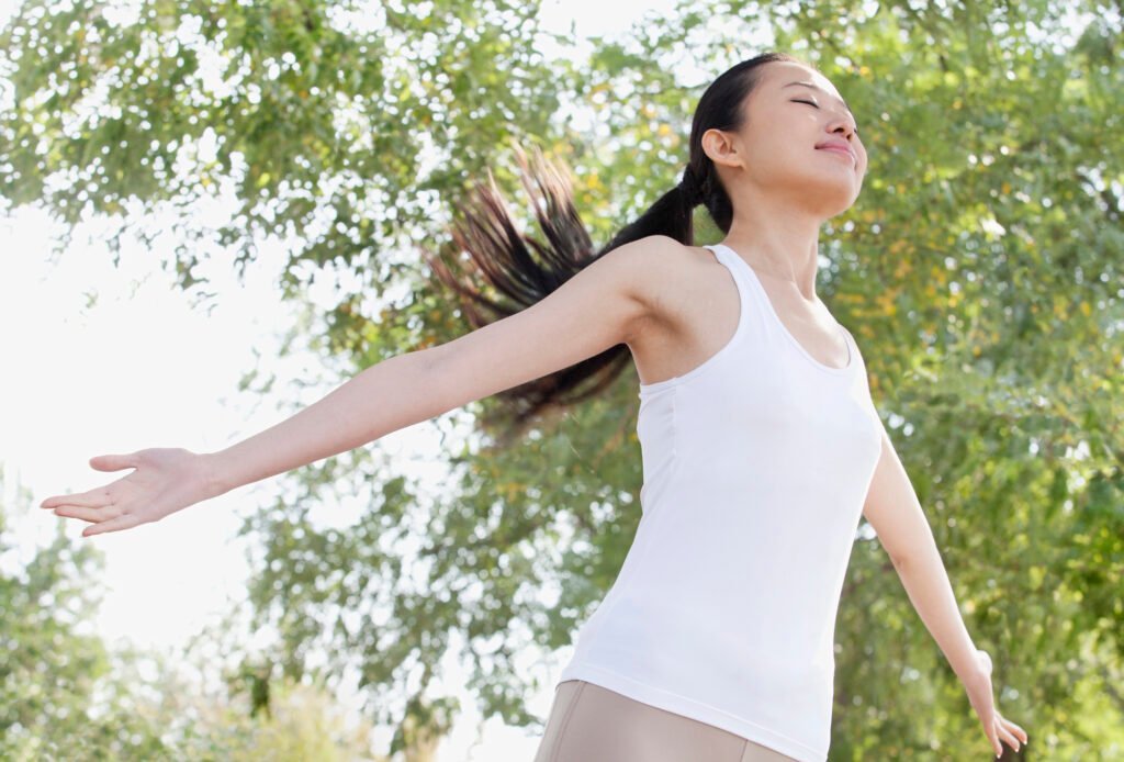 Woman practicing natural, mindful movement outdoors during a somatic yoga practice.