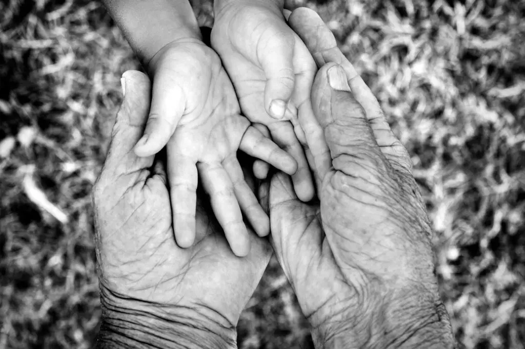 Child’s hand resting in an older adult’s hands, representing connection across generations