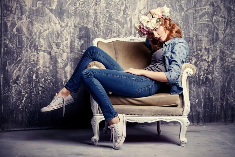 Woman wearing a flower crown, jeans, and sneakers lounging in a vintage armchair.